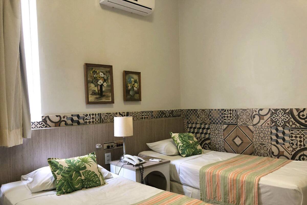 A hotel room with two beds, a washbasin, and a telephone.