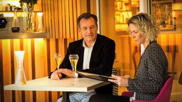 Zwei Personen sitzen an einem Tisch mit einer Champagnerflasche und Gläsern.