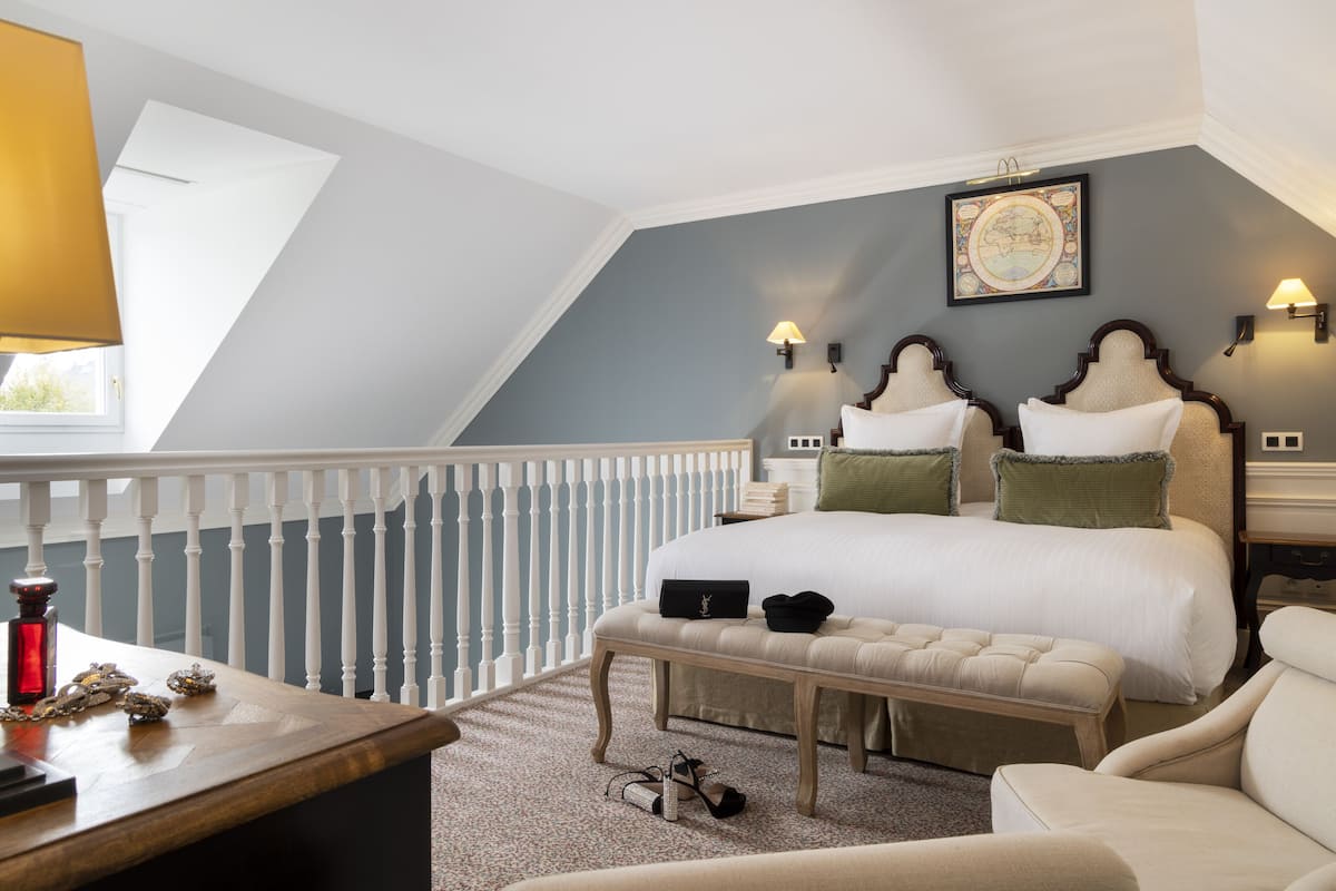 Ein Schlafzimmer mit einem großen Bett, einer Bank, einem Stuhl, einem Schreibtisch und einer Geländer.