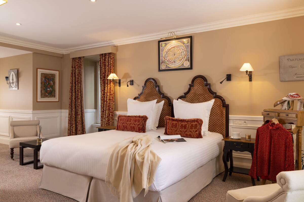 Ein Hotelzimmer mit einem großen Bett, zwei Nachttischen, einem Sessel und einem Kleiderschrank.