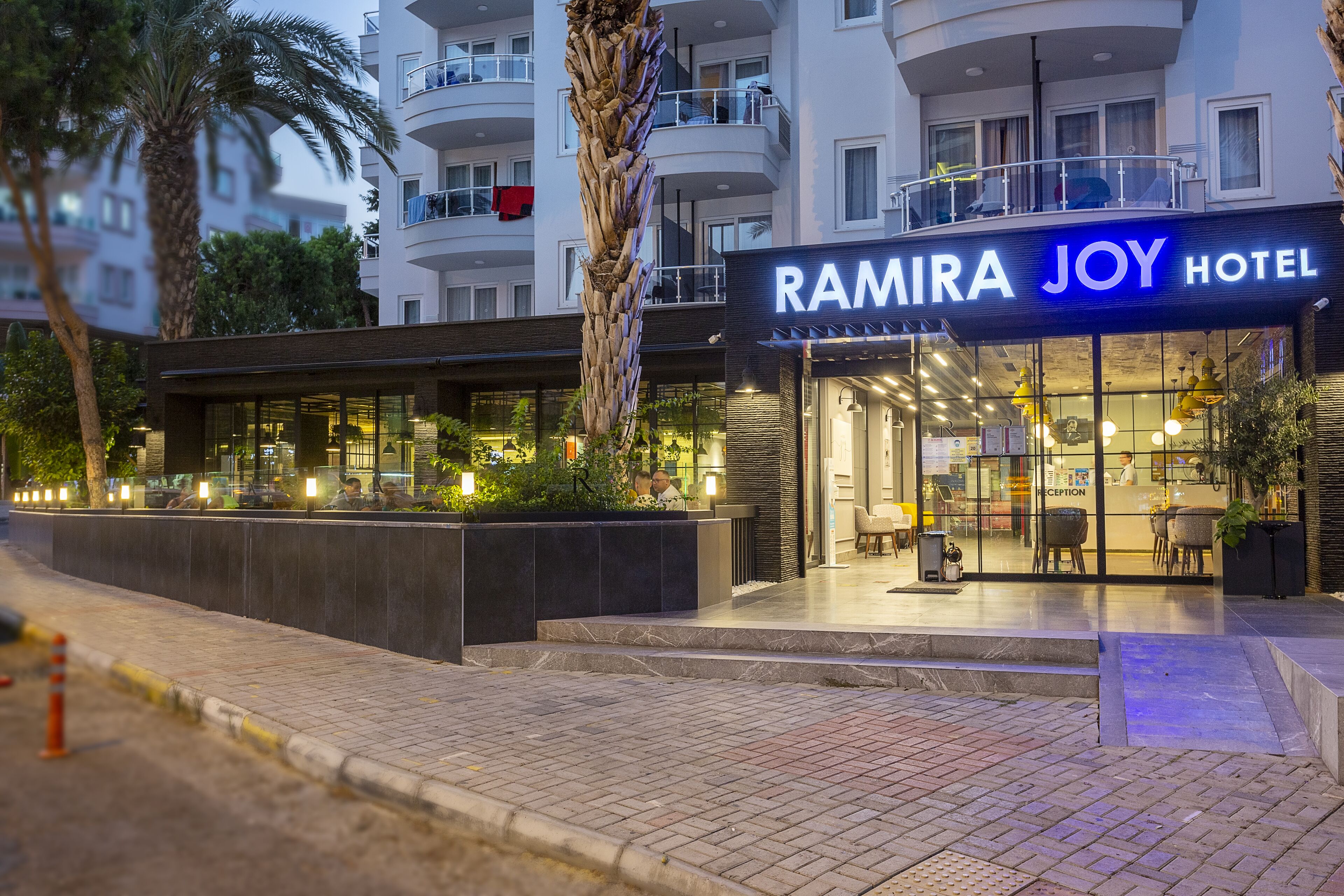 The exterior of Ramira Joy Hotel with a modern facade, a reception area, and a landscaped outdoor space.