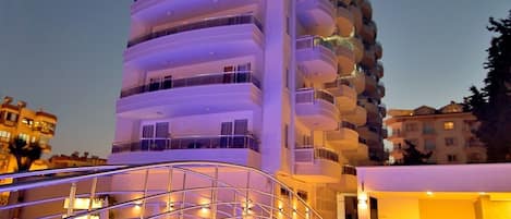 Un hotel moderno con diseño curvo, piscina e iluminación exterior.