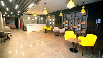 A reception area with a reception desk, yellow chairs, and a bookshelf.