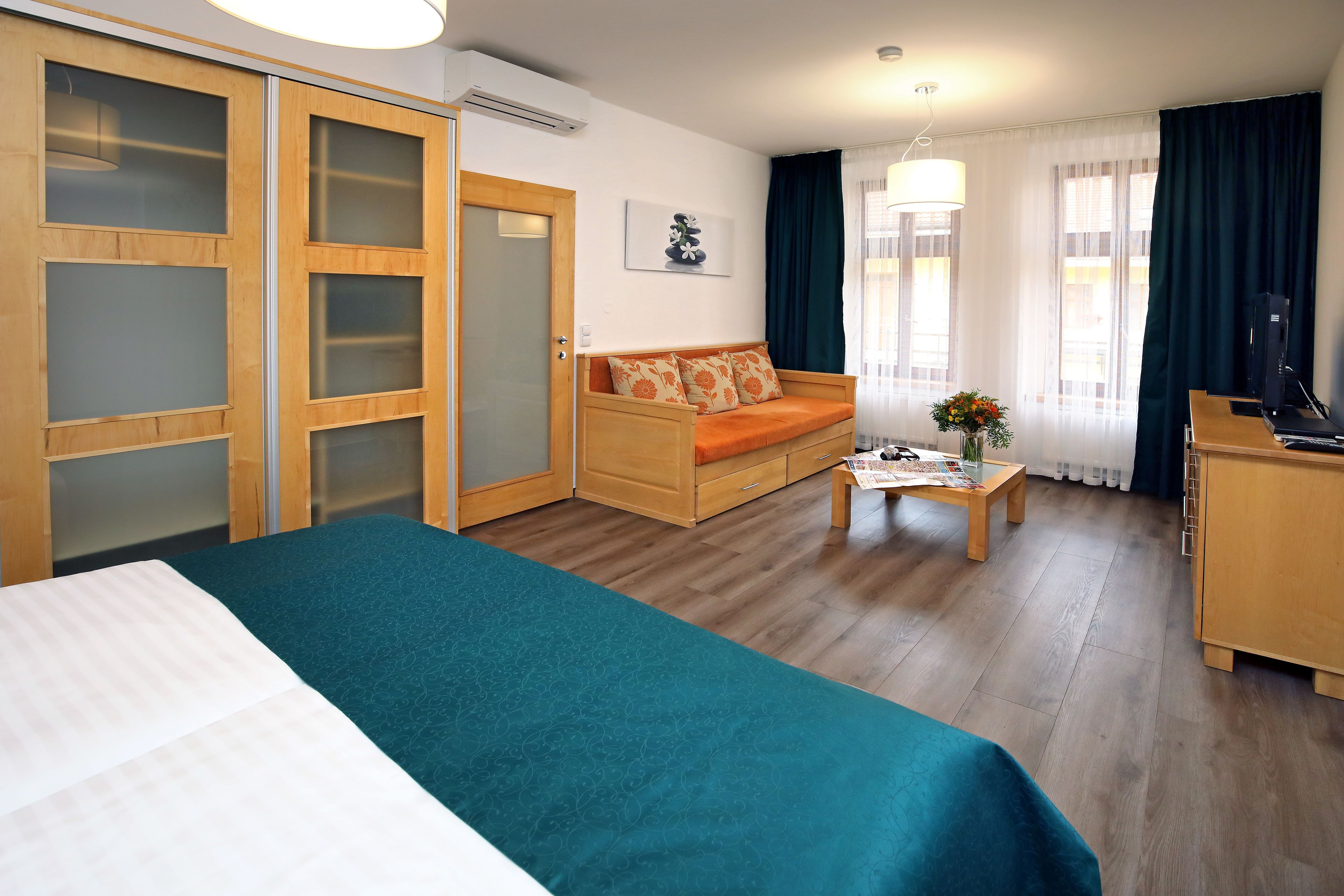 A hotel room with a bed, a sofa, a desk, and a wardrobe.
