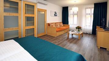 A hotel room with a bed, a sofa, a desk, and a wardrobe.