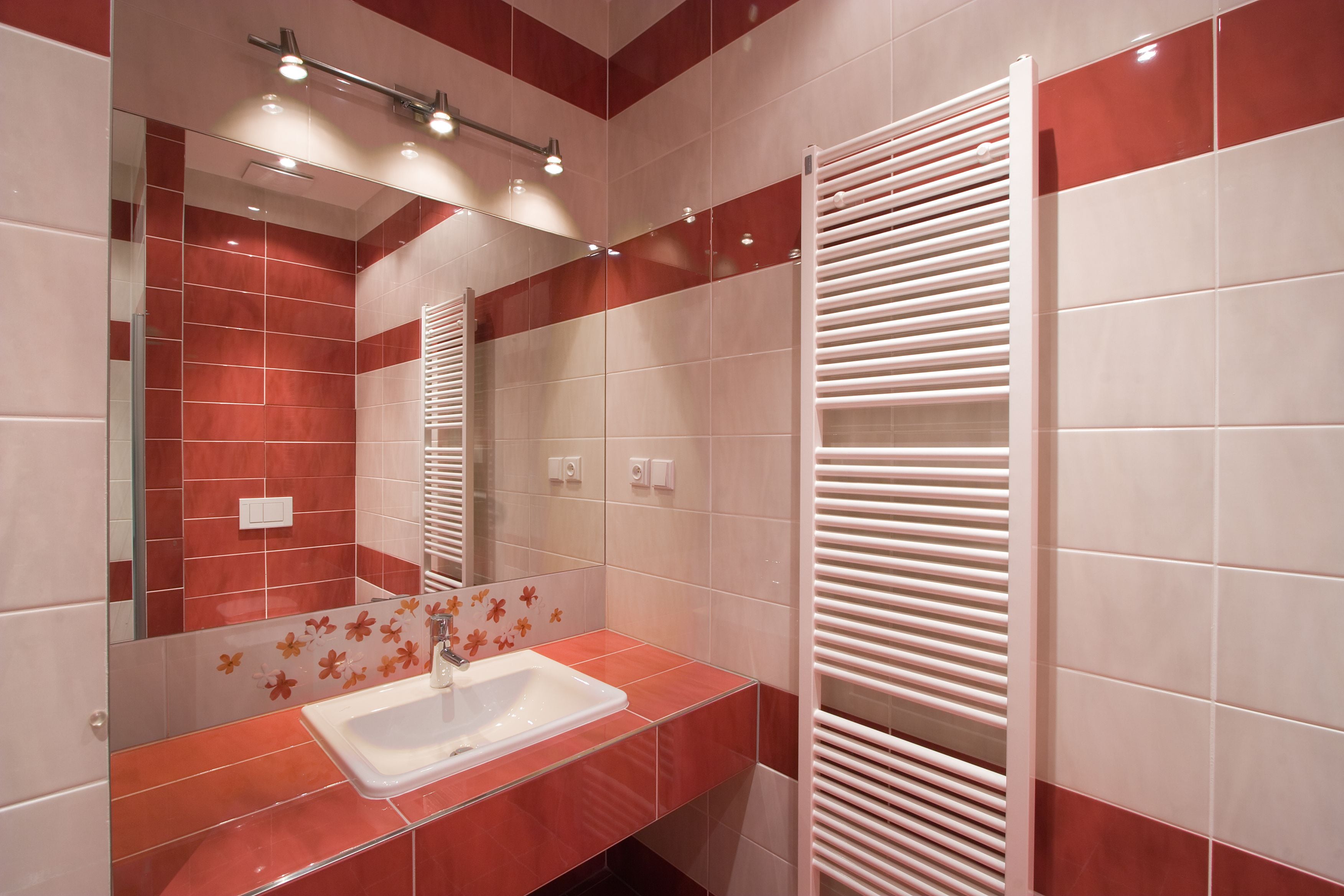 A modern bathroom with a glass shower enclosure, a white sink, and a towel rack.