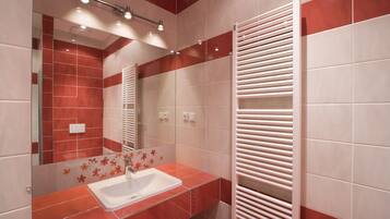A modern bathroom with a glass shower enclosure, a white sink, and a towel rack.