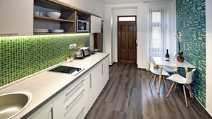 A modern kitchen with a white countertop, a sink, and a dining area with a table and chairs. - Andel Apartments Praha (Prague)