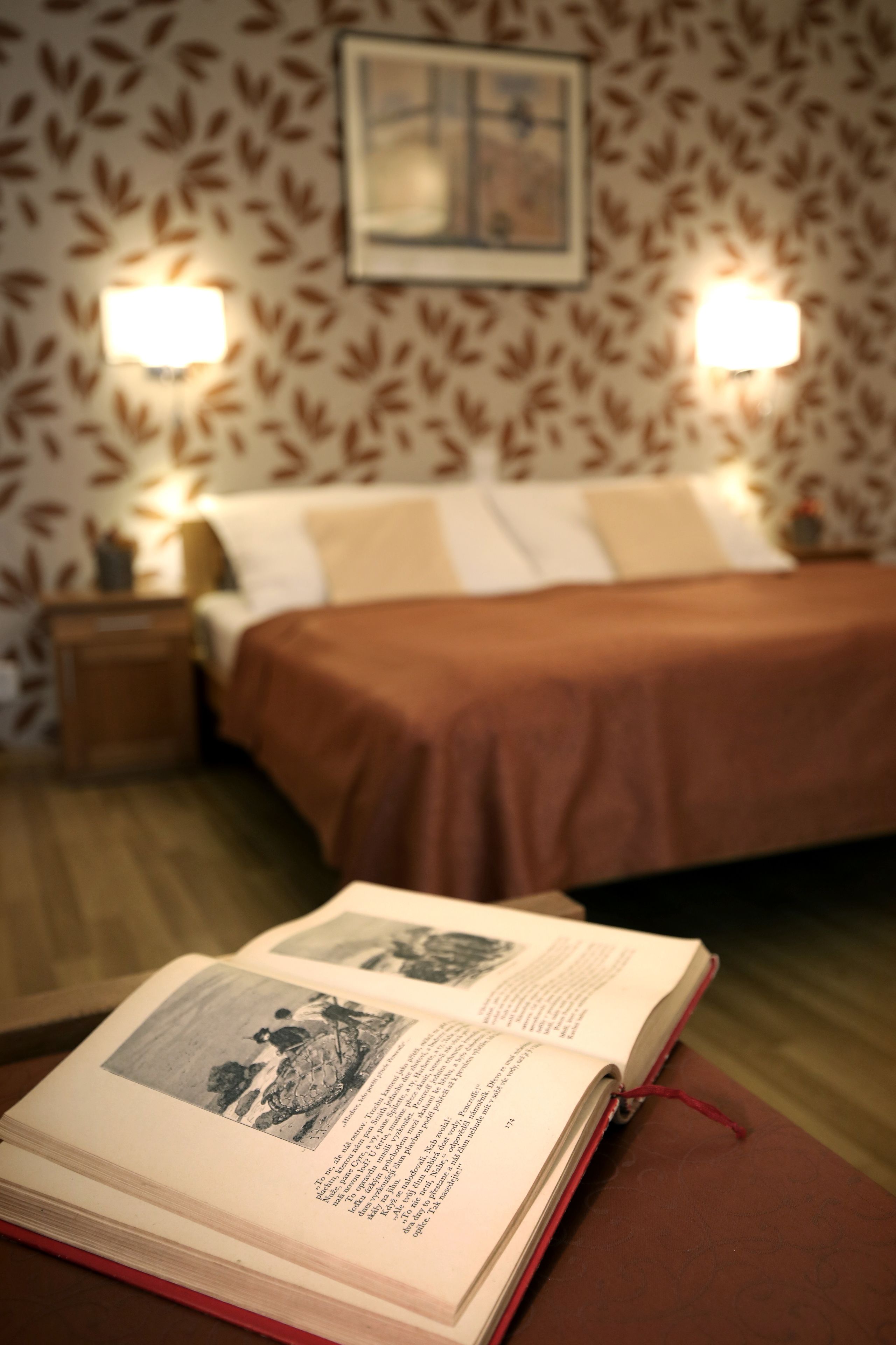 Ein Hotelzimmer mit einem Bett, einem Nachttisch und einem Buch auf dem Bett.
