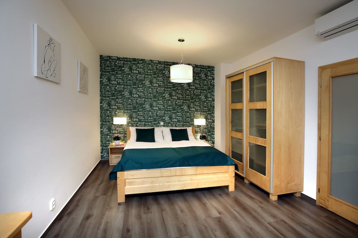 A bedroom with a bed, wooden wardrobe, and a green wall with 'LOVE' written on it.