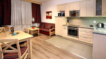 Una cocina compacta con armarios de madera, una mesa de comedor con sillas y un sofá.