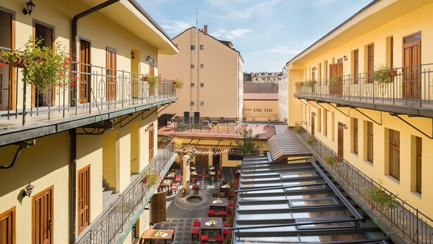A courtyard with outdoor seating, a central fountain, and multiple balconies with railings. - Andel Apartments Praha (Prague)