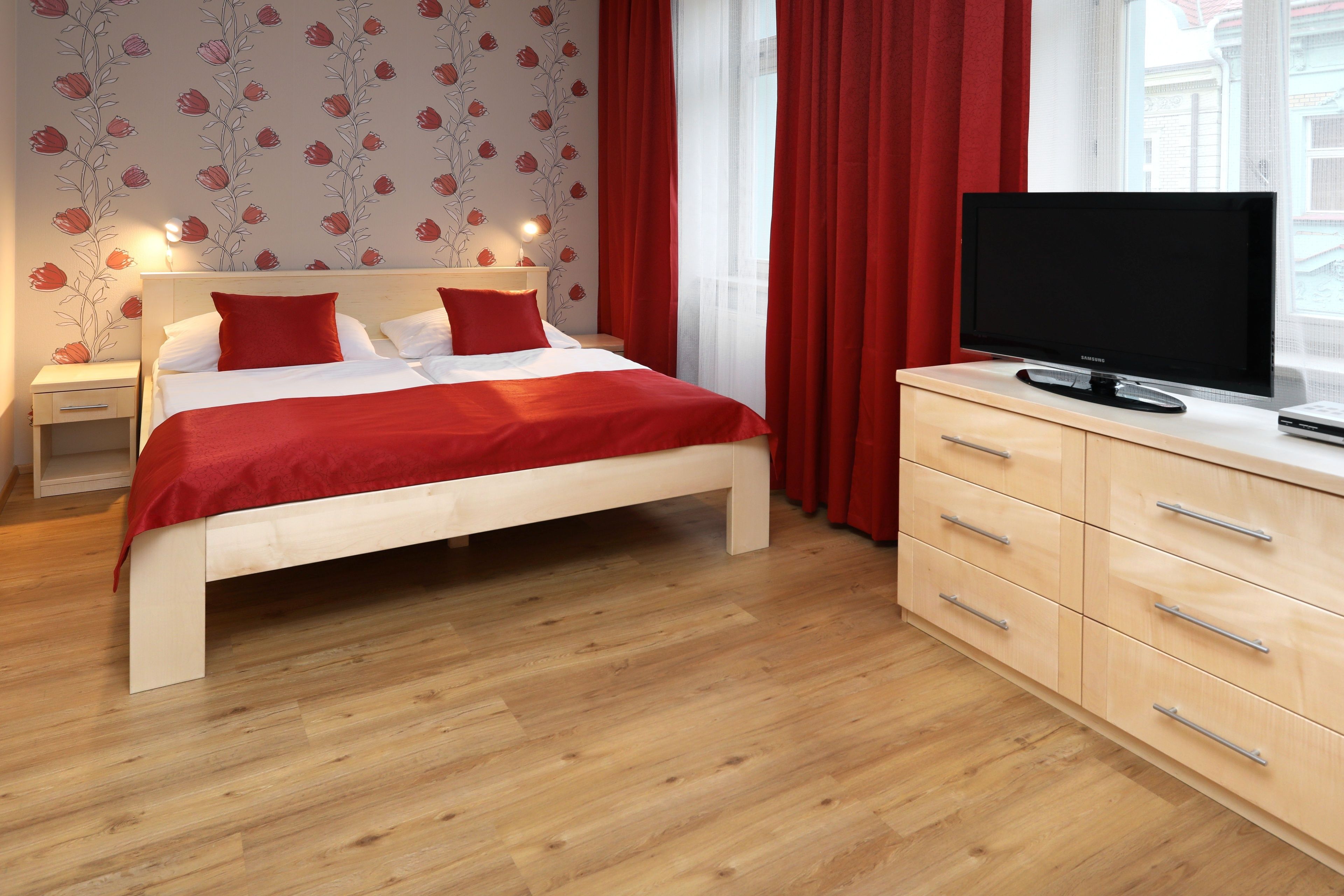A modern bedroom with a bed, bedside tables, a TV, and a dresser.