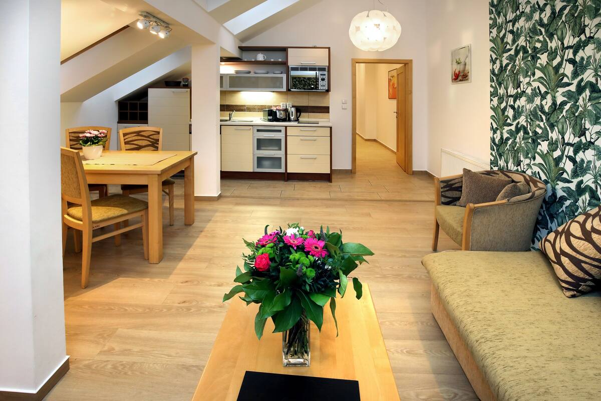 A compact living space with a dining area, kitchenette, and a sofa with a decorative pillow.