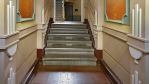A grand staircase with ornate railings and a mural on the walls. - Andel Apartments Praha (Prague)