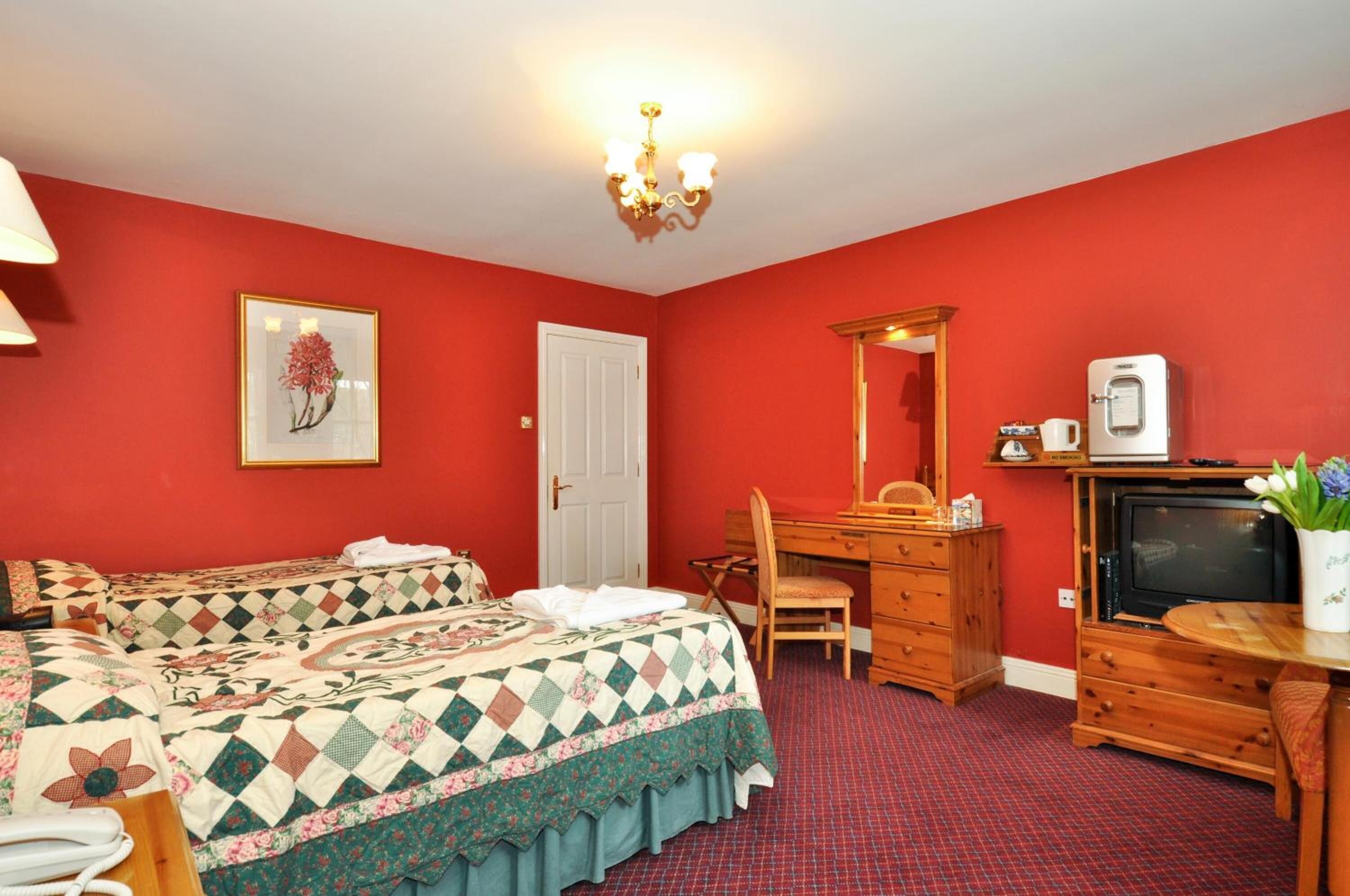 A room with two beds, a desk, a chair, a television, and a coffee machine.