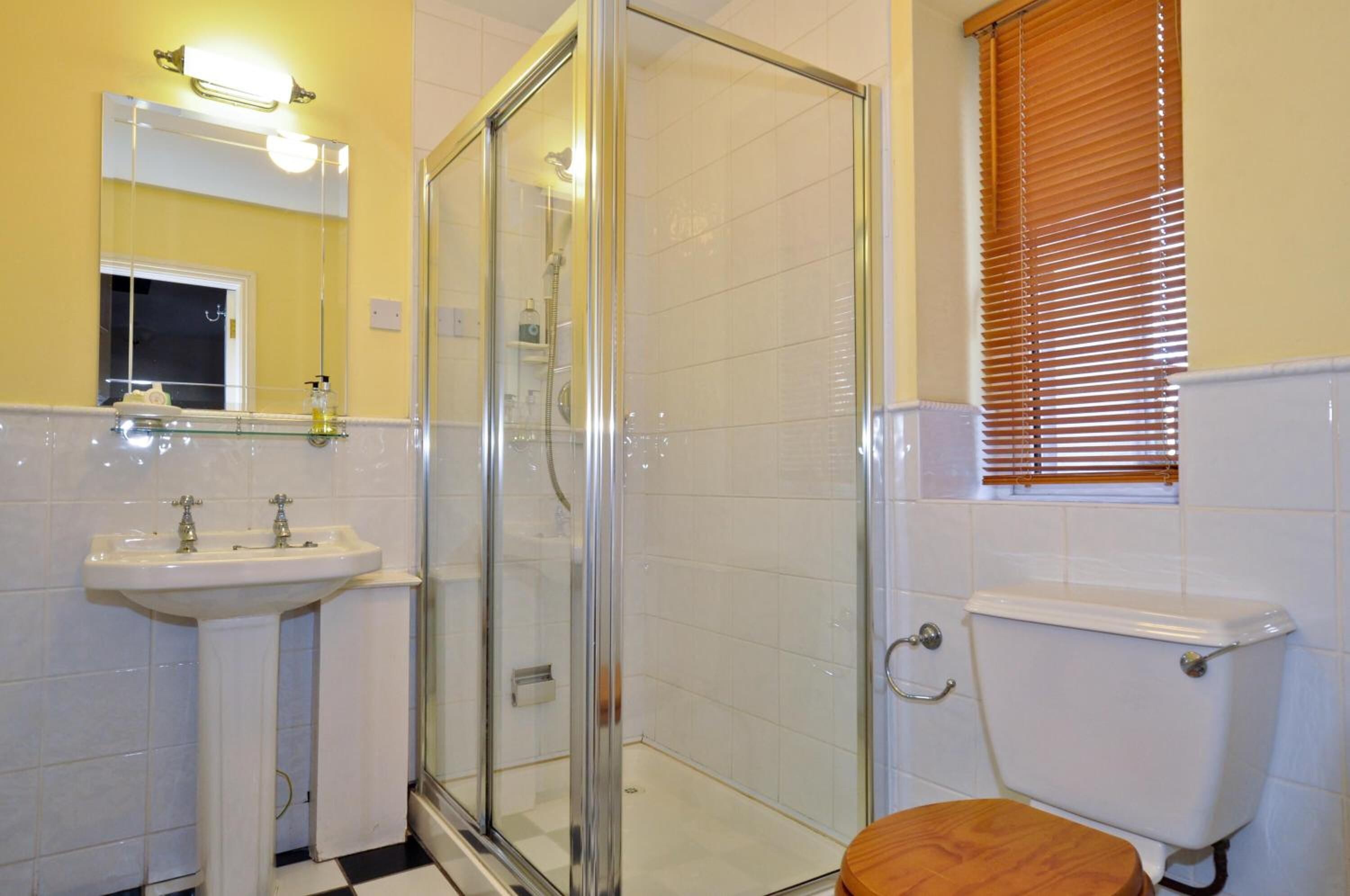 A bathroom with a glass-enclosed shower, a white sink, and a toilet.