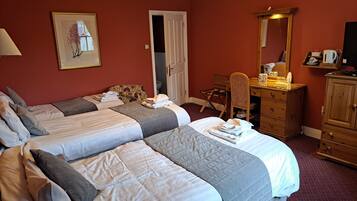 A hotel room with two beds, a desk, a chair, a dresser, and a mirror.