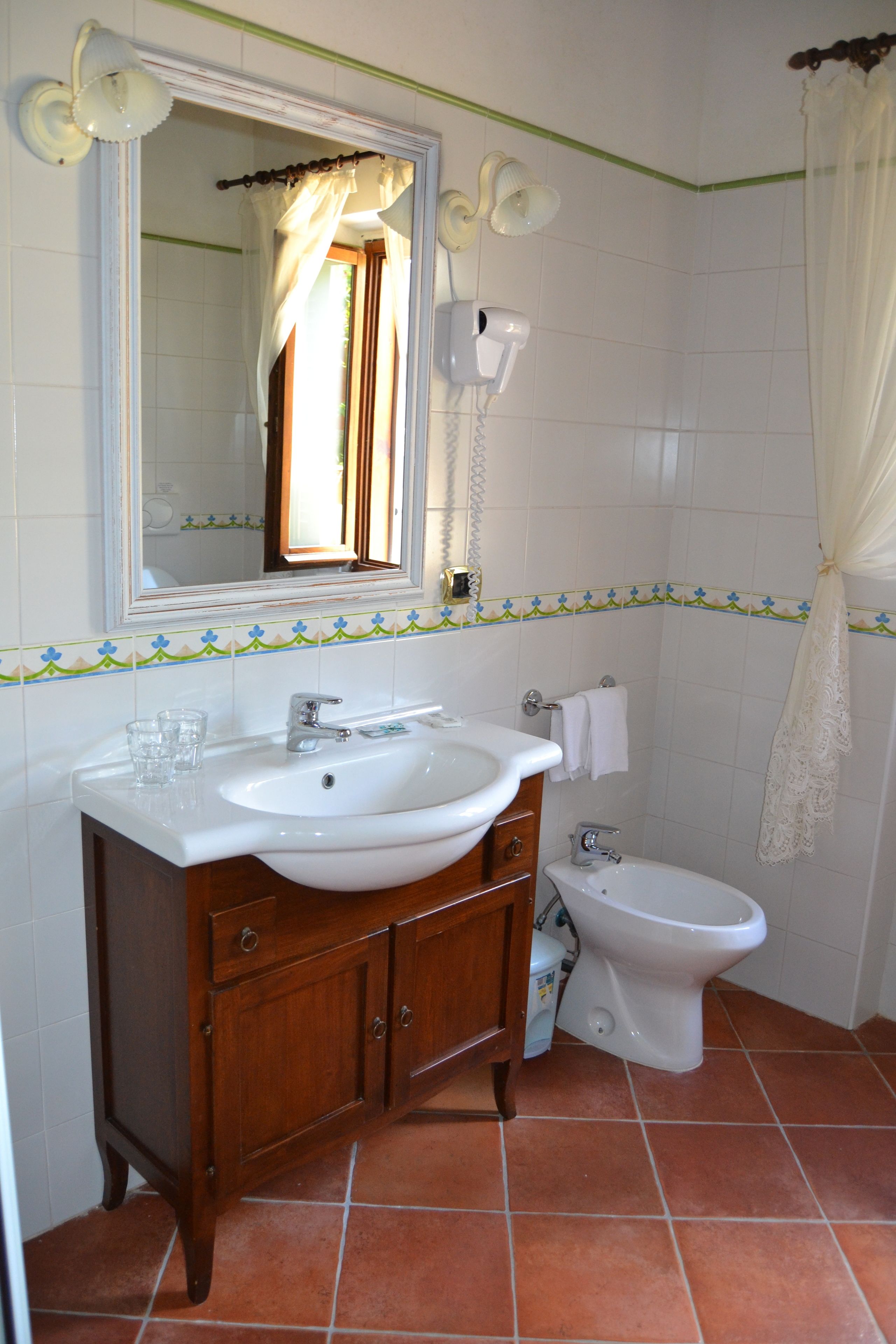 Ein Badezimmer mit weißem Waschbecken, Waschtisch, Spiegel und Toilette.