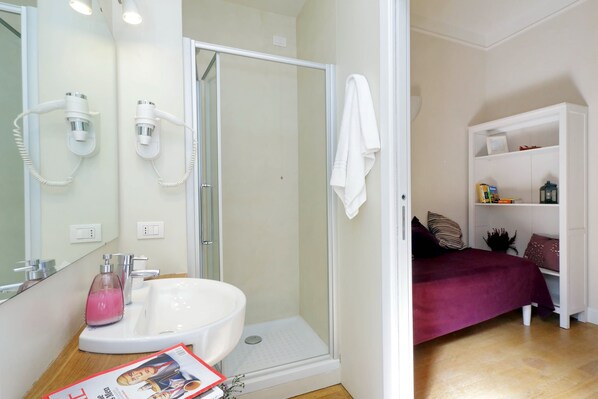 A bathroom with a shower, sink, and a magazine on the counter.