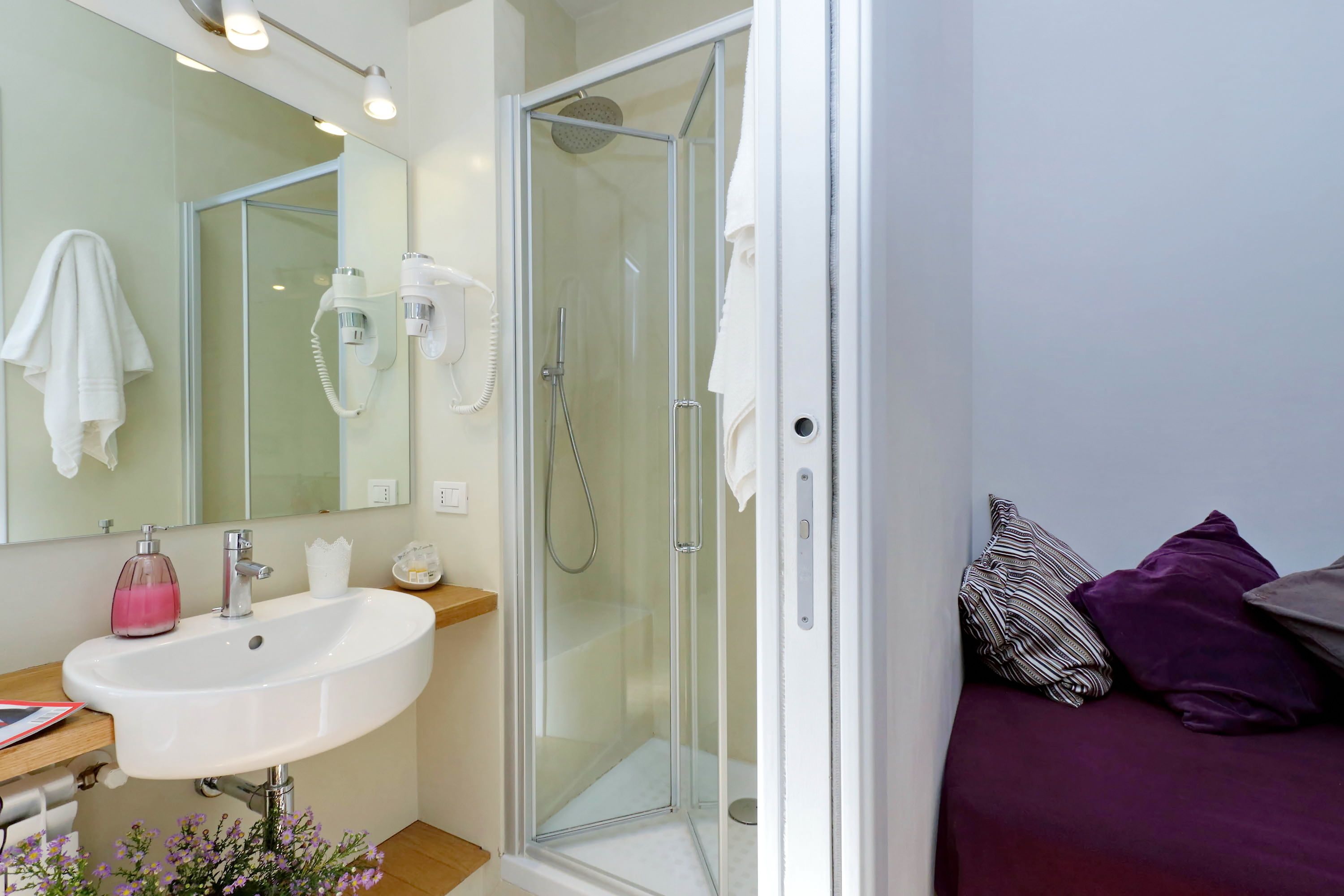A modern bathroom with a glass-enclosed shower, a white sink, and a mirror.