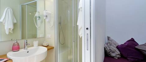 A modern bathroom with a glass-enclosed shower, a white sink, and a mirror.