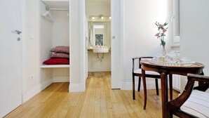 A room with a wooden floor, a white sink, a mirror with lights, a chair, and a table with a tray. - Amaranto Romano (Rome)