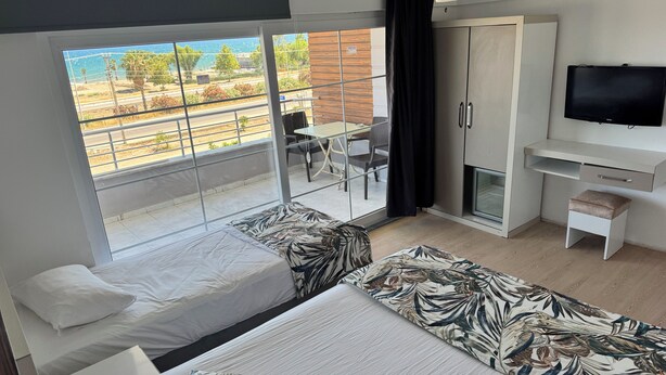 Ein Hotelzimmer mit Balkon, einem Bett mit gemusterten Textilien, einem Schreibtisch mit Stuhl und einem Fernseher.
