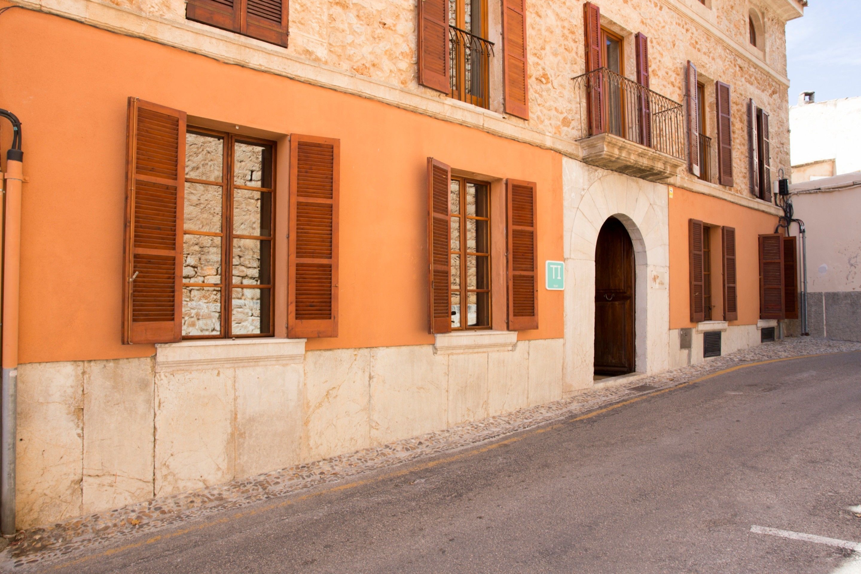 Un edificio con paredes anaranjadas, contraventanas de madera y fachada de piedra.