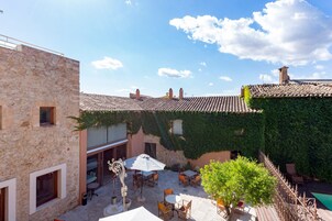 Un edificio de piedra con techo de tejas, zona de estar al aire libre y piscina.