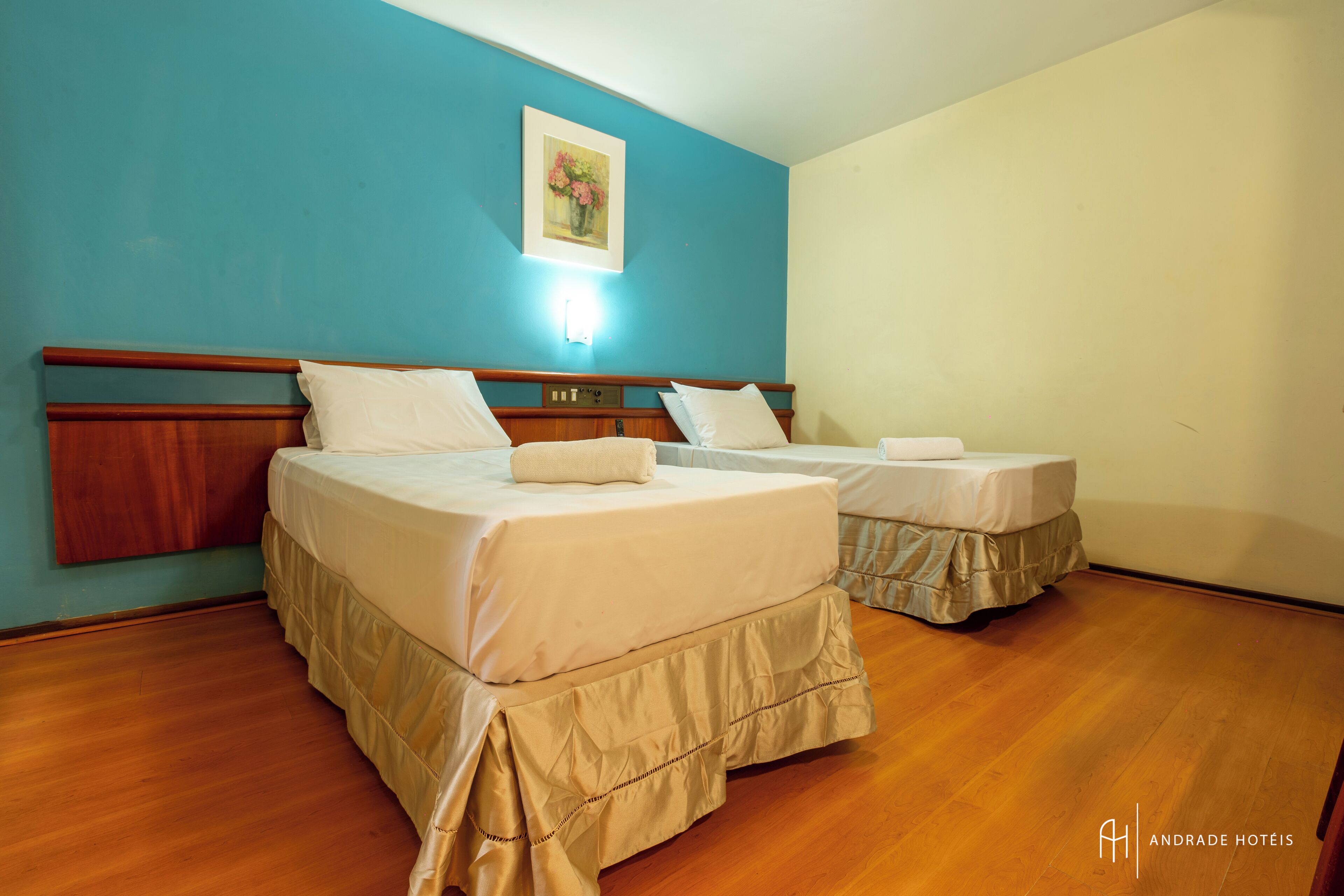 A hotel room with two beds, wooden headboards, and a painting on the wall.