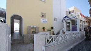 A hotel named 'Hotel Mylos' with a signboard, a reception desk, and a staircase leading to the entrance. - Hotel Mylos (Santorini)