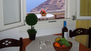 A table with a view of the sea, a bottle, and a bowl of fruit. - Hotel Mylos (Santorini)