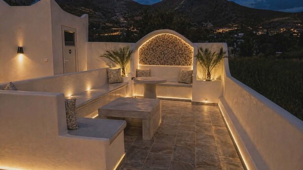 Una terraza en la azotea con suelo de piedra, zona de estar y un muro decorativo.