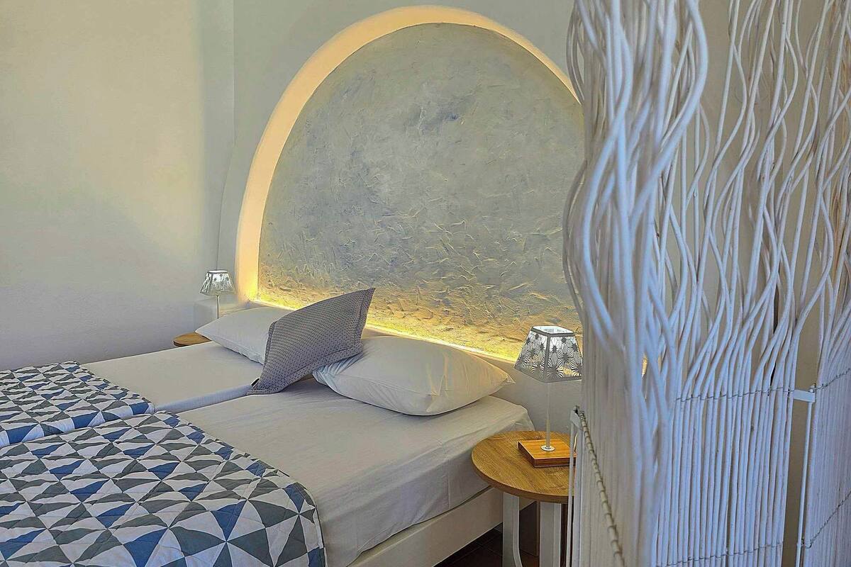 A bedroom with a bed, a nightstand, a lamp, and a decorative wall.