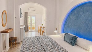 Un dormitorio con una cama grande, un escritorio, una silla y vistas al balcón.