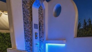 Un espacio exterior moderno para spa, con pared de piedra, fuente de agua e iluminación LED azul.