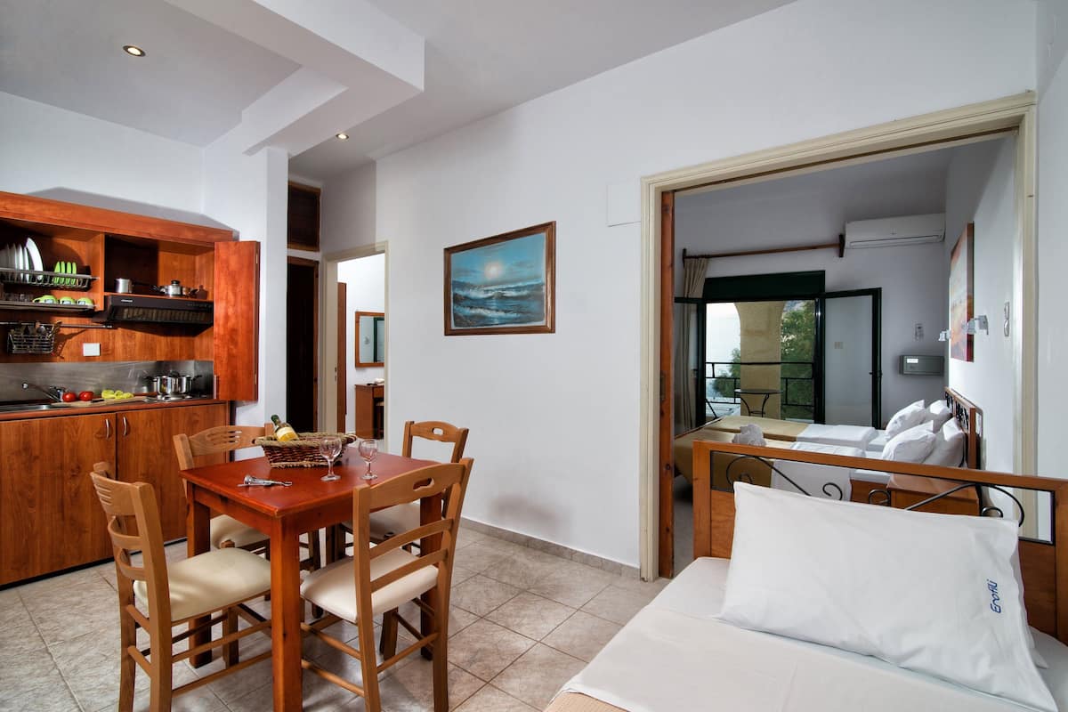 A compact hotel room with a bed, a dining table, and a kitchenette.