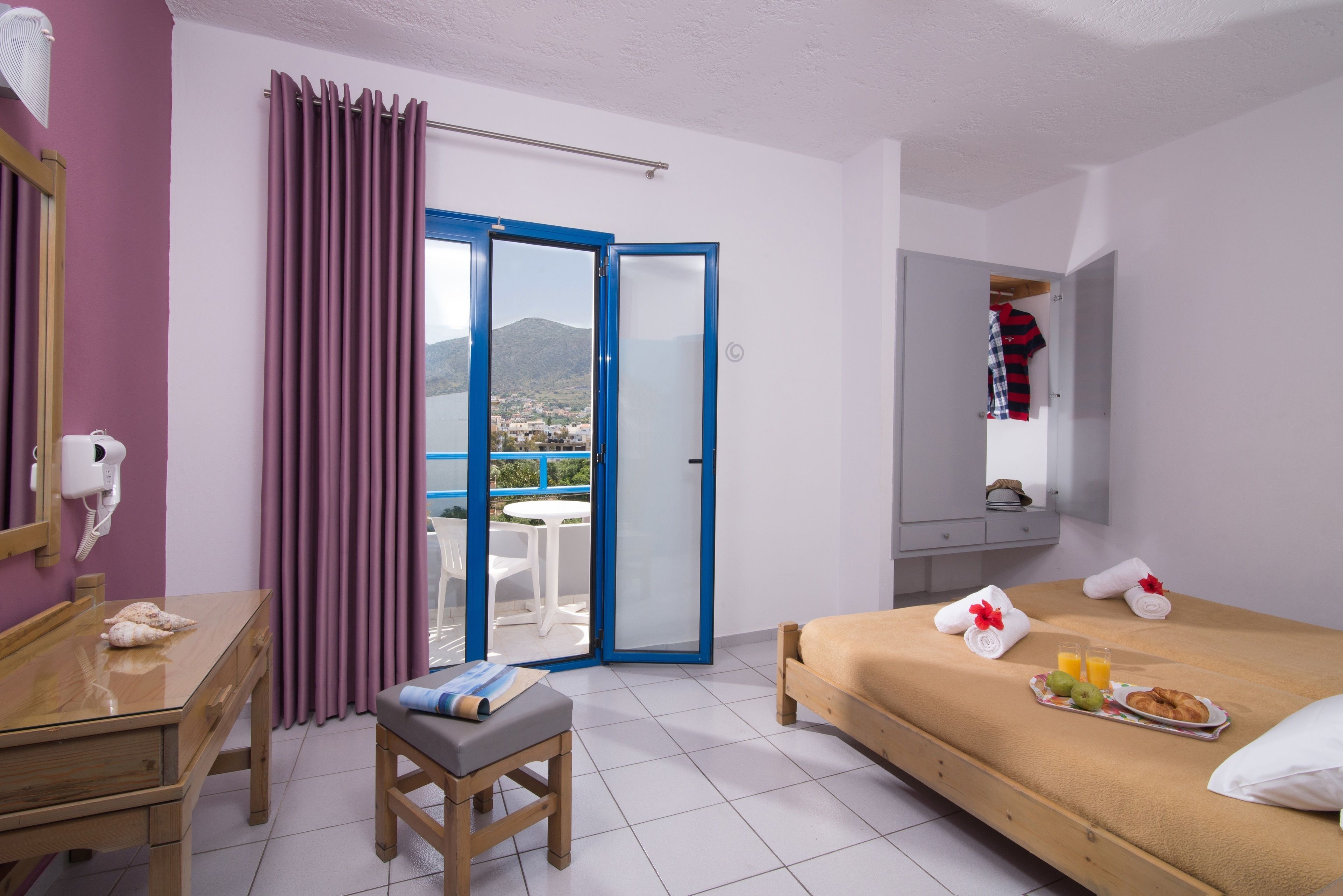 Una camera d'albergo con un letto, una scrivania, una sedia, un tavolino e vista sull'esterno.