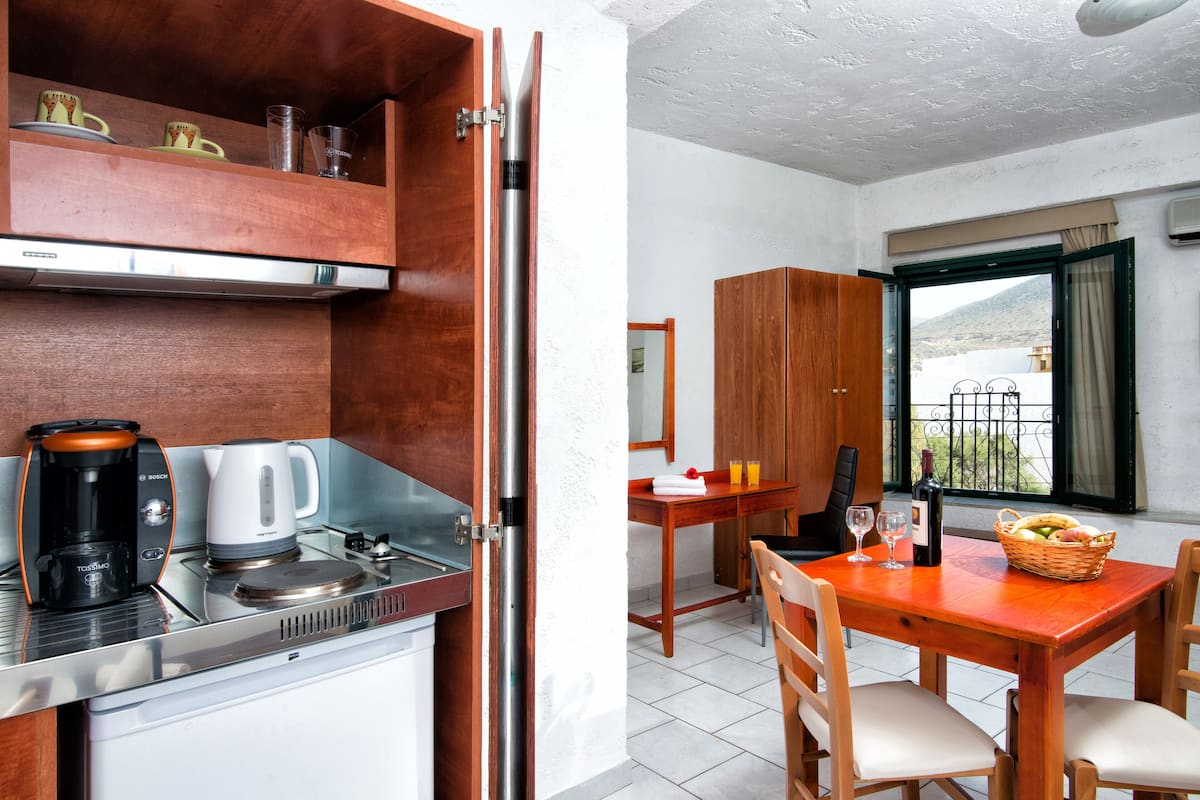 A compact kitchen with a coffee maker, kettle, and a dining area with a table and chairs.