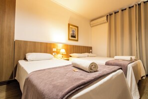A hotel room with two beds, a wooden headboard, a framed picture on the wall, and a window with curtains. - Golden Star (Curitiba)