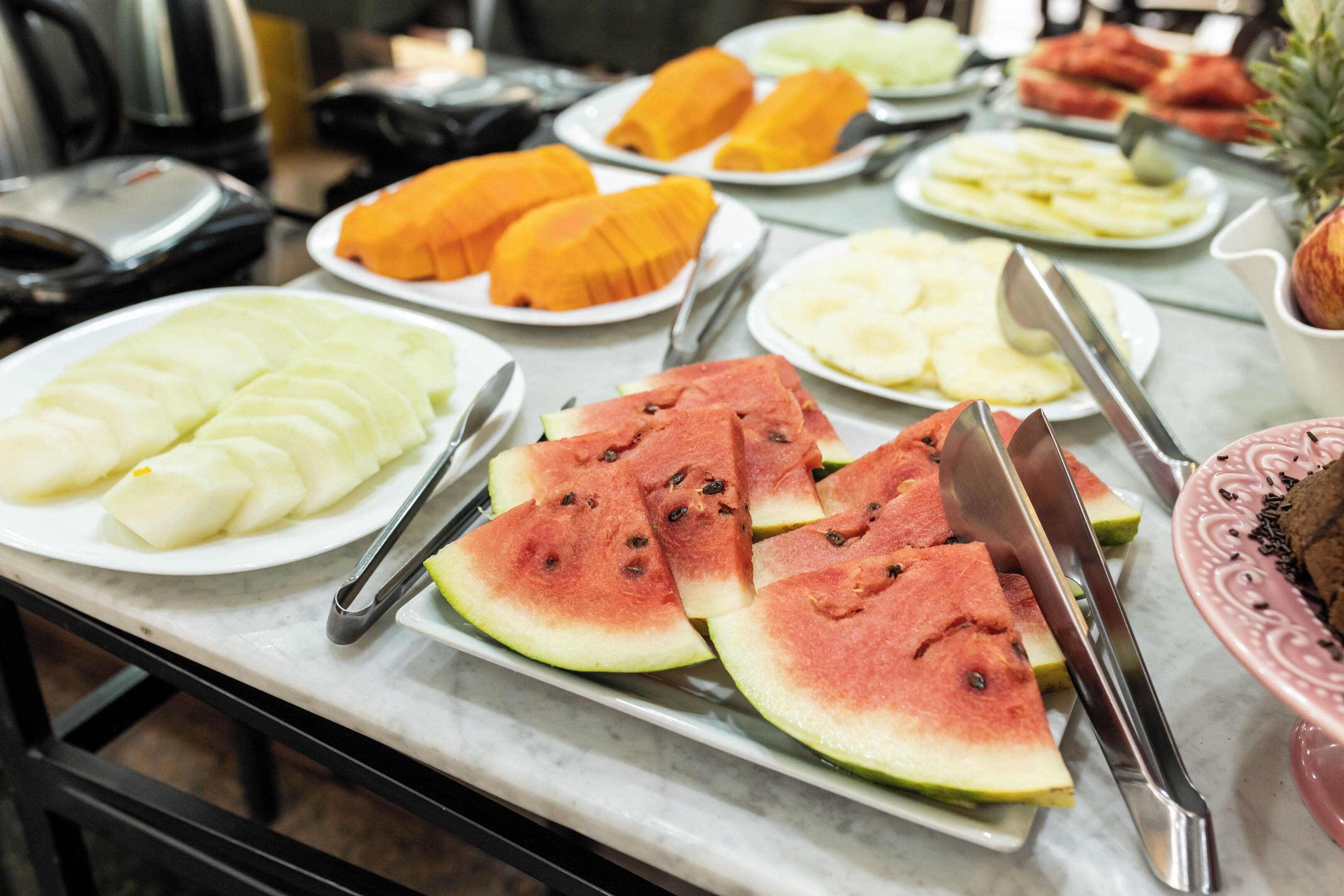 Una mesa de buffet con diversas frutas y verduras, como sandía y piña.