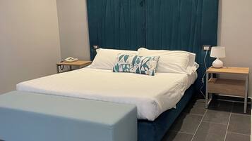 Un dormitorio moderno con una cama grande, una mesita de noche con lámpara y una pequeña mesa redonda.