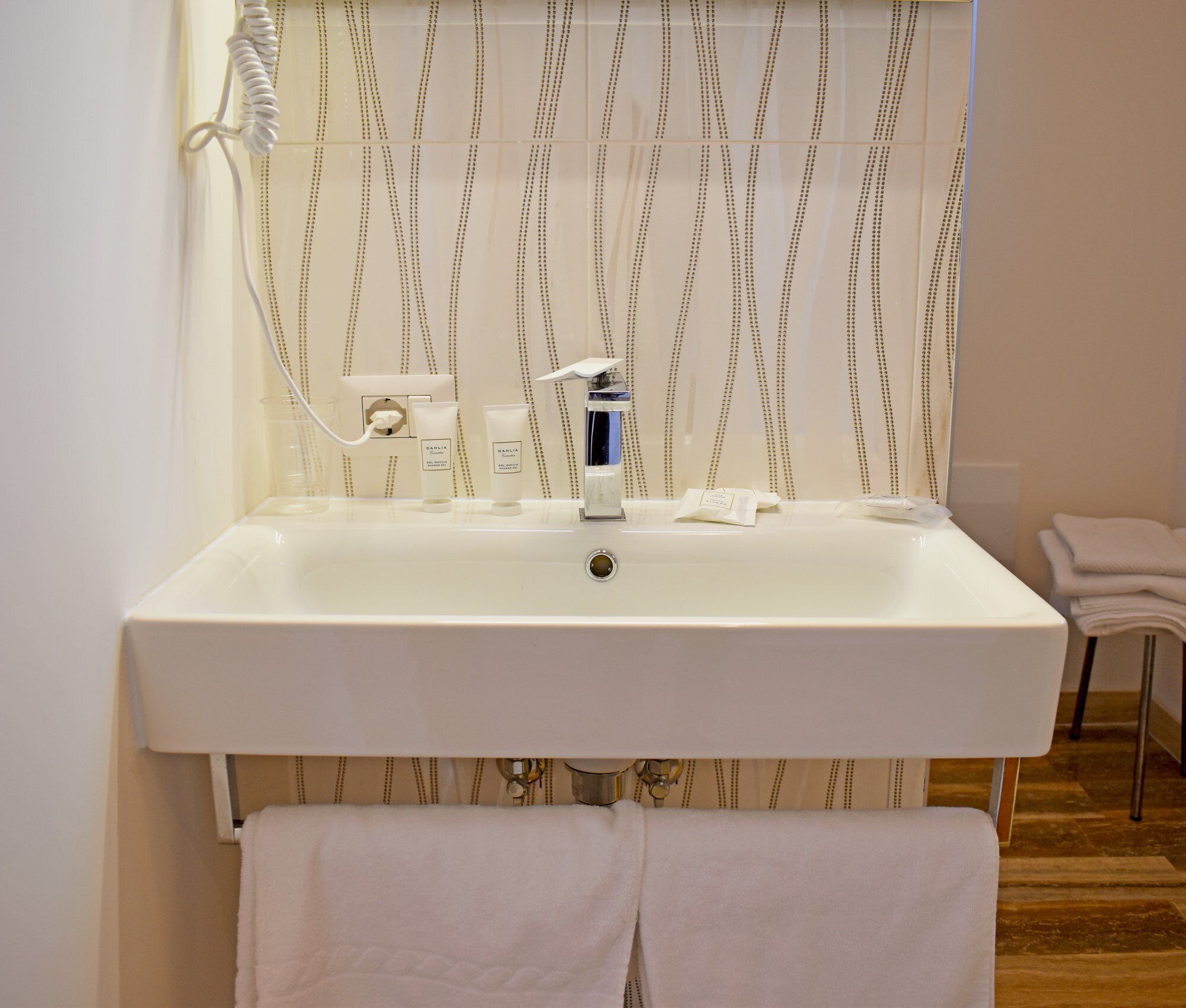 A bathroom with a white sink, a mirror, and a towel rack.