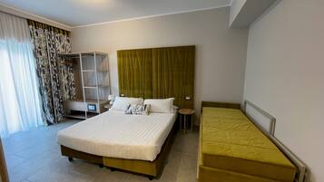 A hotel room with a large bed, a smaller bed, a wardrobe, and a seating area.