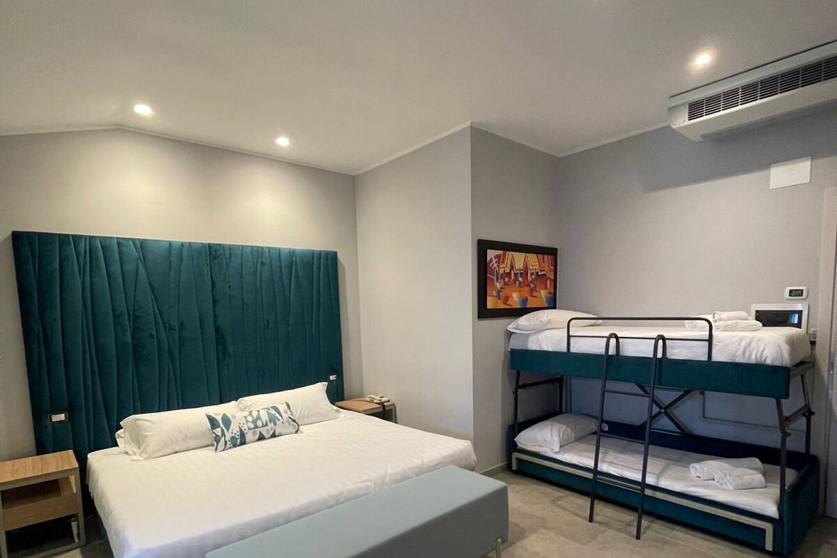 Ein modernes Schlafzimmer mit einem großen Bett, einem Etagenbett, einem Nachttisch und einer Wand-Klimaanlage.