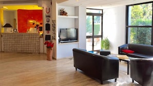 A modern living room with a black leather sofa, a flat-screen TV mounted on the wall, and a wooden floor.