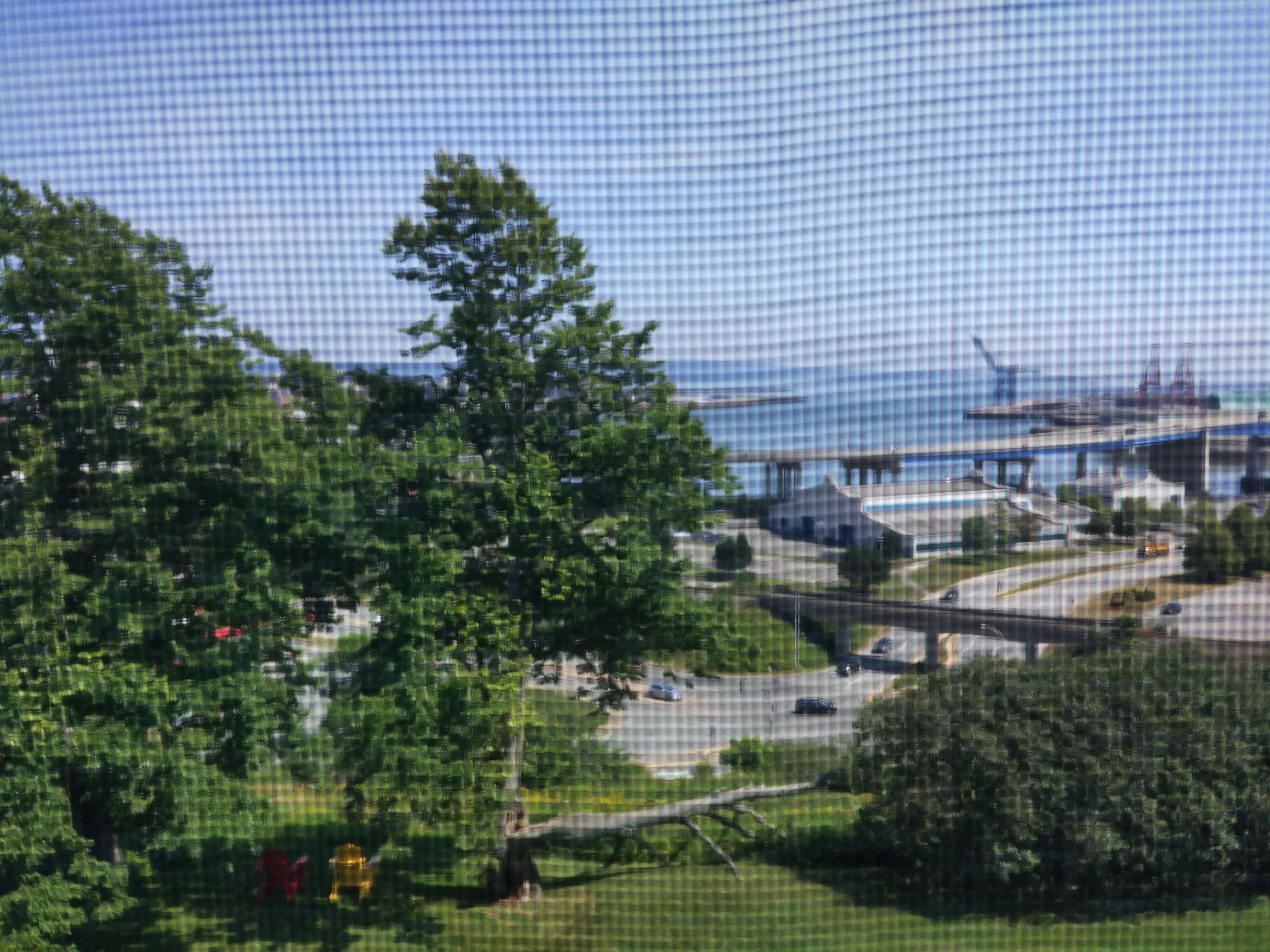 A view of a coastal area with a bridge, greenery, and a body of water.