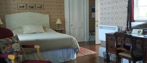 A bedroom with a bed, a chair, a desk, and a door.