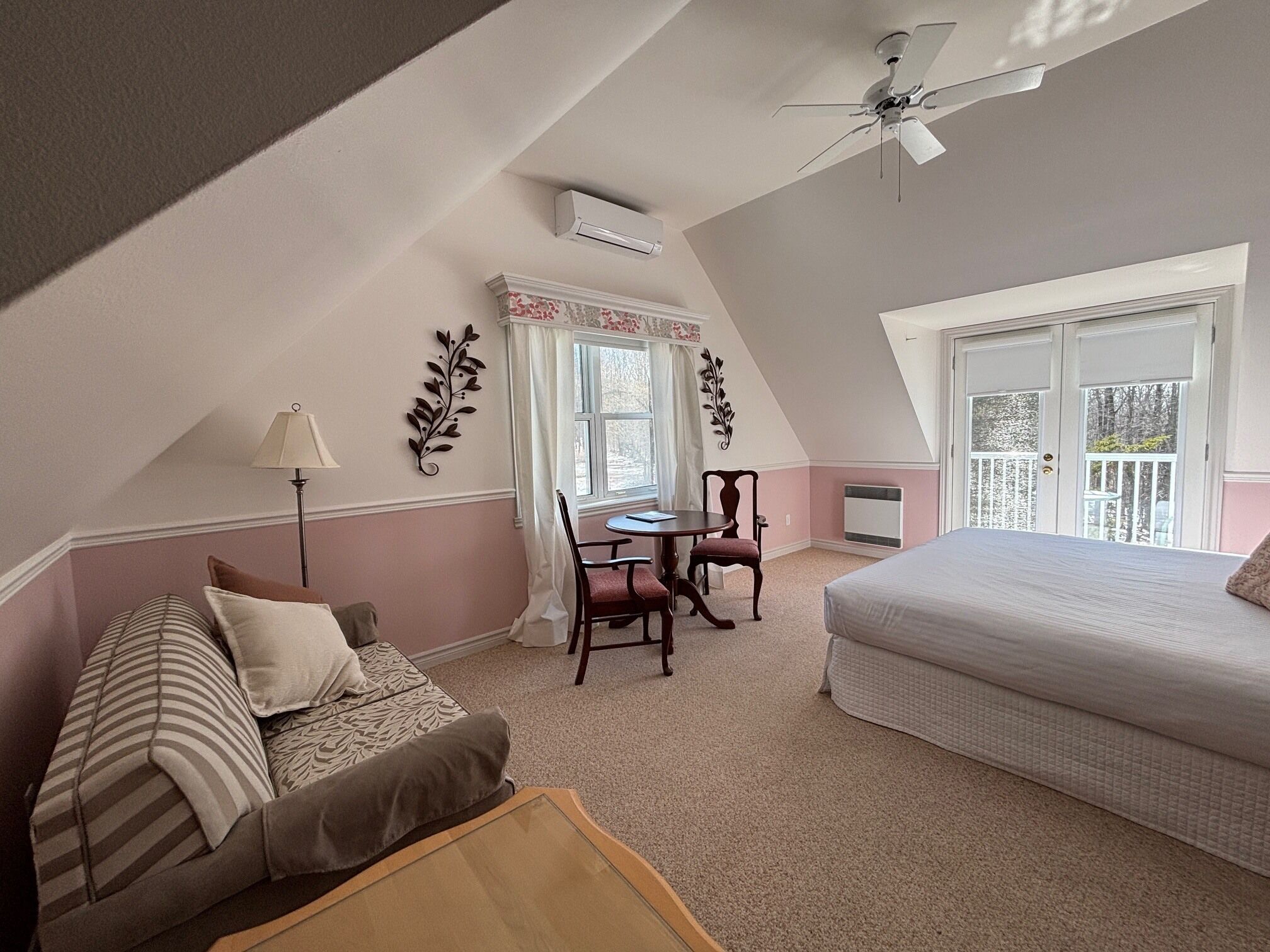 Une chambre à coucher avec un lit, un bureau et une chaise, une fenêtre avec des rideaux et un ventilateur de plafond.